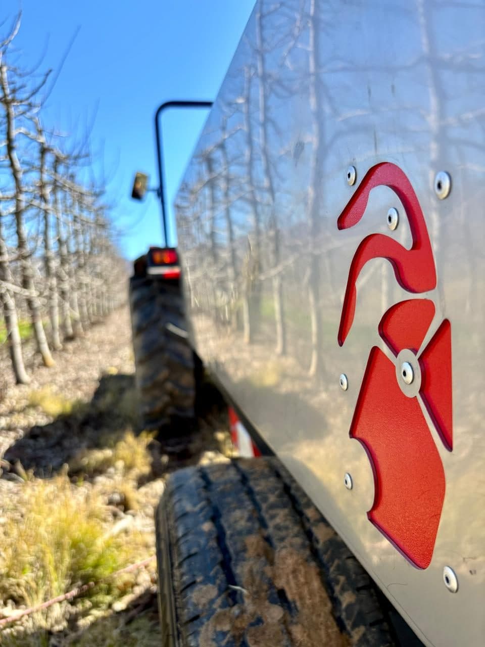 Red Ant branding on the side of a machine working between apple rows